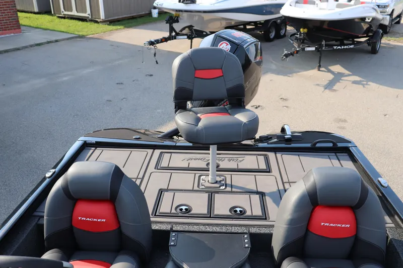 Slide: The Image of 2025 Tracker Savage 215 boat interior with gray and red seating, parked outdoors. - 15