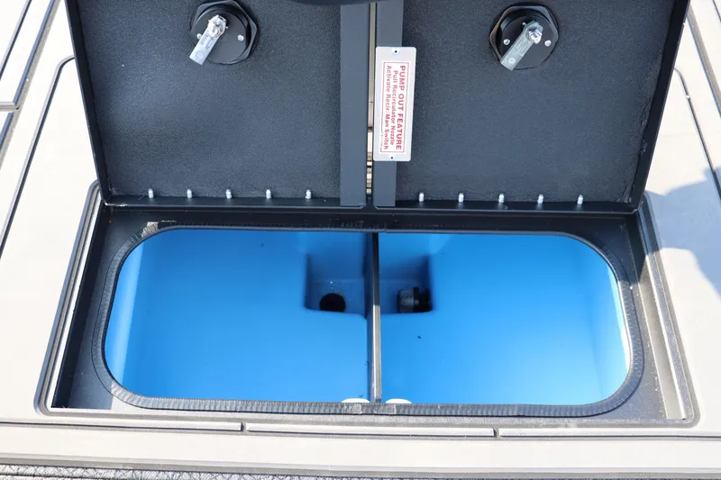 Slide: The Image of Open storage compartment on 2025 Tracker Savage 215 boat, featuring blue interior and pump-out feature. - 17