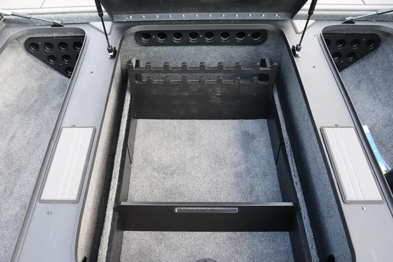 Slide: The Image of 2025 Tracker Savage 215 boat storage compartment with rod holders and carpeted interior. - 8