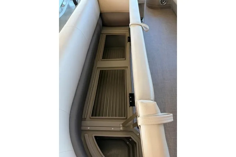 Slide: The Image of 2025 Sun Tracker Party Barge 18 DLX interior storage compartment with beige seating. - 5