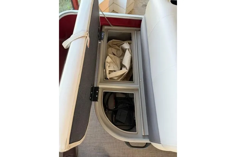 Slide: The Image of 2025 Sun Tracker Party Barge 18 DLX storage compartment with open seat revealing interior space. - 10