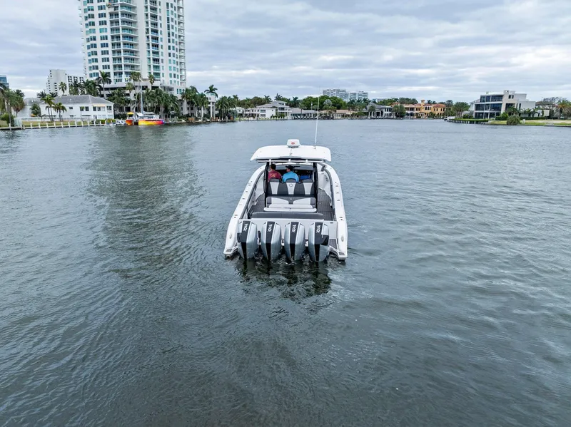 Slide: The Image of Fountain 43NX boat cruising on a calm waterway, surrounded by modern buildings. - 3