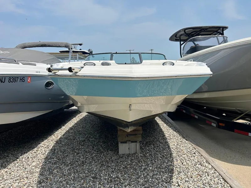 Slide: The Image of 2021 NauticStar 203 DC boat on gravel, flanked by other boats. - 2