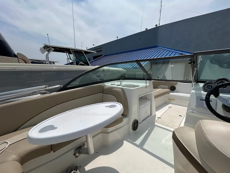 Slide: The Image of 2021 NauticStar 203 DC boat interior with seating and table, docked under a blue roof. - 9
