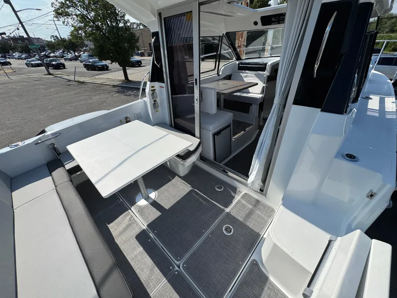 Slide: The Image of 2025 Jeanneau NC 795 Series 2 boat interior with seating and table, docked outdoors. - 3
