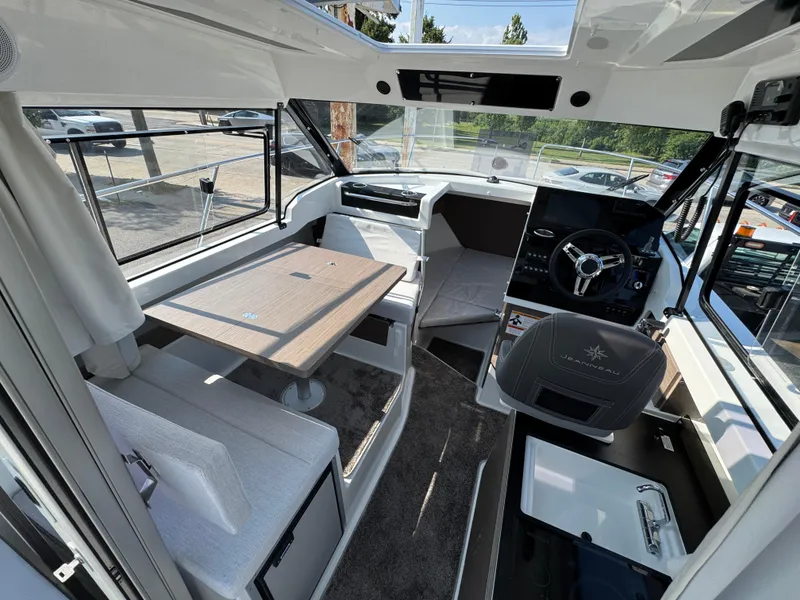 Slide: The Image of Interior of 2025 Jeanneau NC 795 Series 2 boat, featuring helm, seating, and table. - 7