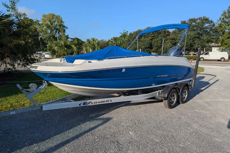 The Image of 2021 Stingray 192 SC boat on trailer, blue and white, parked outdoors. - 0