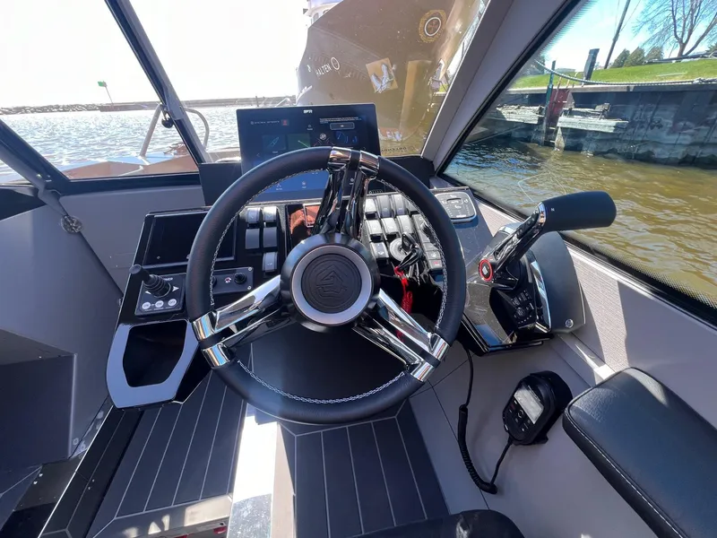 Slide: The Image of 2024 G-Force boat cockpit with steering wheel and control panel, dockside view. - 8