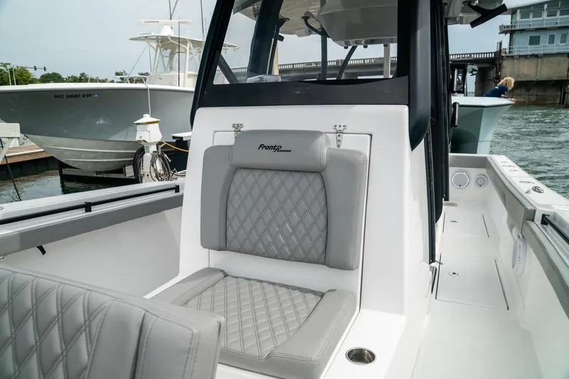 Slide: The Image of 2026 Front Runner 33 CC boat interior with gray quilted seating at a marina. - 11