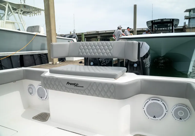 Slide: The Image of 2026 Front Runner 33 CC boat interior with cushioned seating and speakers at dock. - 21