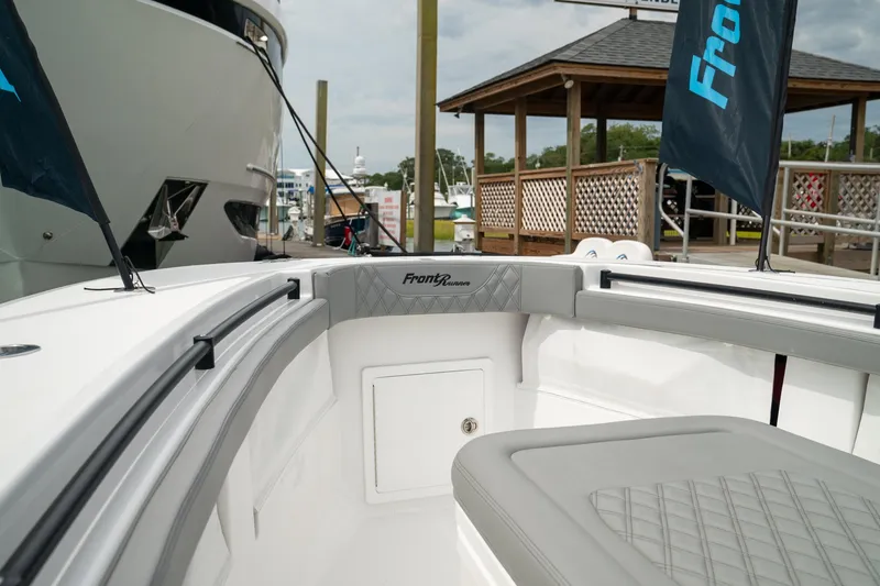 Slide: The Image of 2026 Front Runner 33 CC boat interior with seating and storage, docked near a marina. - 5