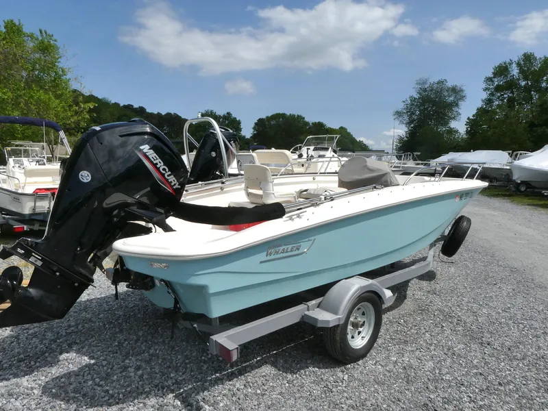 Slide: The Image of 2024 Boston Whaler 160 Super Sport boat on trailer, outdoors, with Mercury engine. - 2
