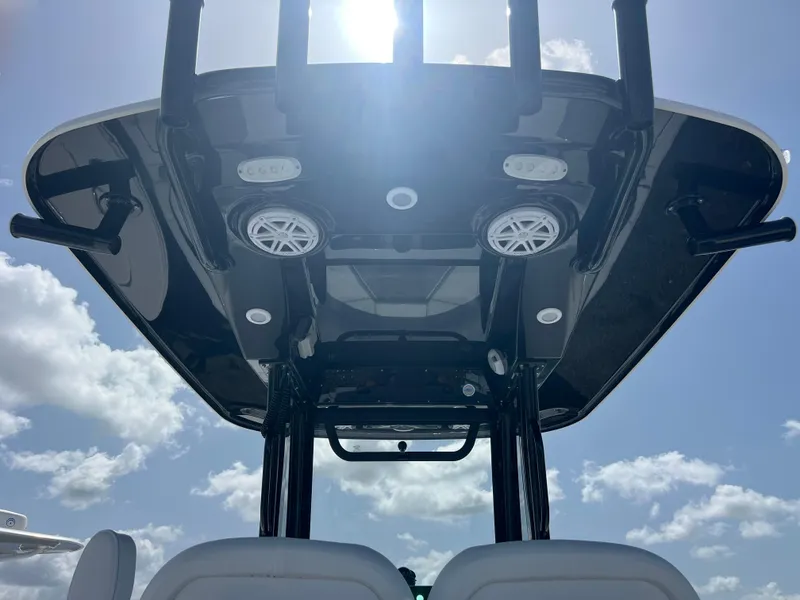 Slide: The Image of 2025 Sportsman Open 232 Center Console boat, T-top view, speakers, sunny sky background. - 10