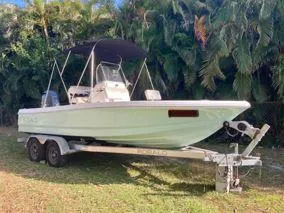 The Image of 2016 Robalo 206 Cayman boat on trailer, parked outdoors with lush greenery background. - 0