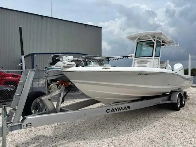 Slide: The Image of 2022 Caymas 28 Twin boat on trailer, parked outdoors near a building. - 2