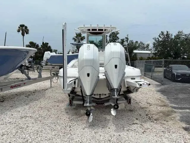 Slide: The Image of 2022 Caymas 28 Twin boat with dual outboard engines, parked on gravel. - 4