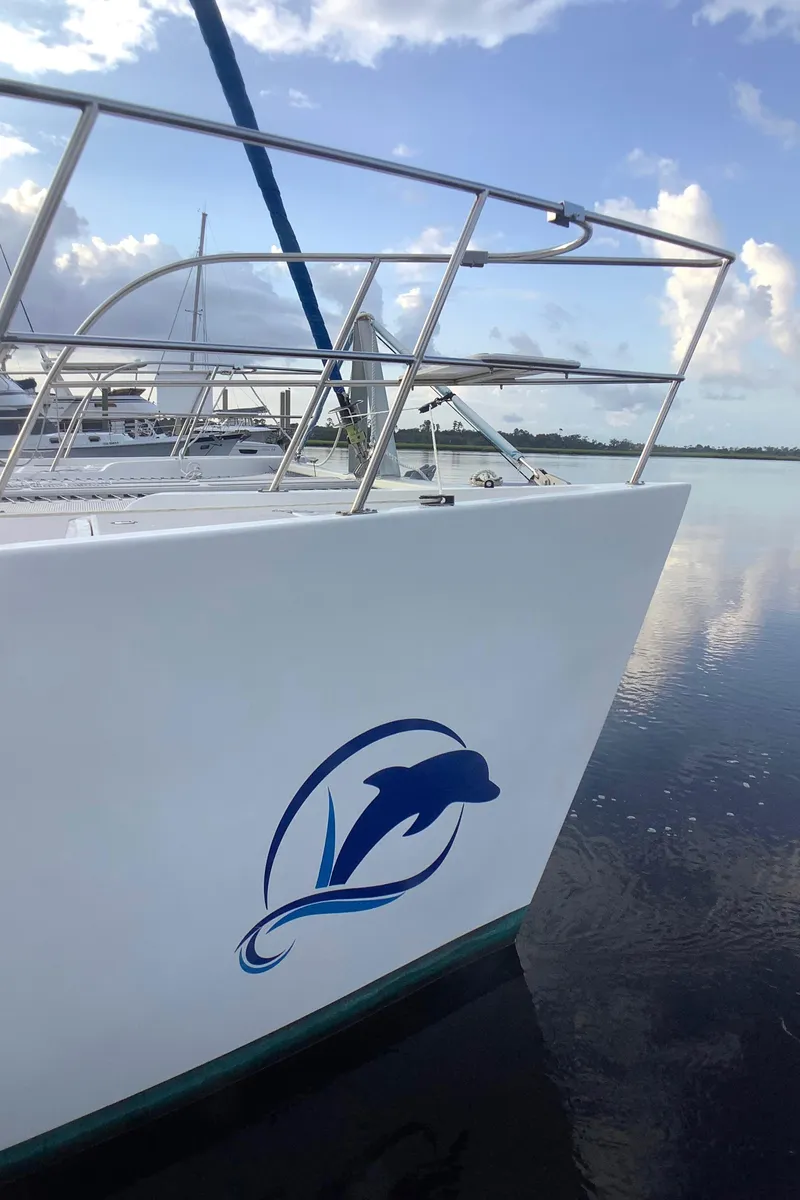 Slide: The Image of 2021 Royal Cape Catamarans Majestic 570 Flybridge, dolphin logo, docked on calm water. - 1