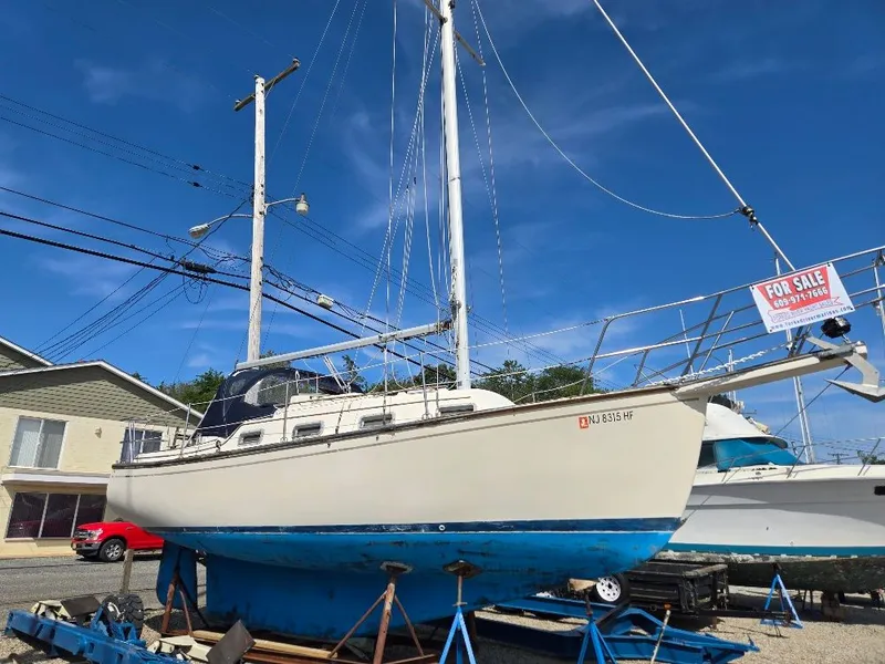 The Image of 1986 Island Packet IP27 sailboat for sale, displayed on a stand under a clear blue sky. - 0