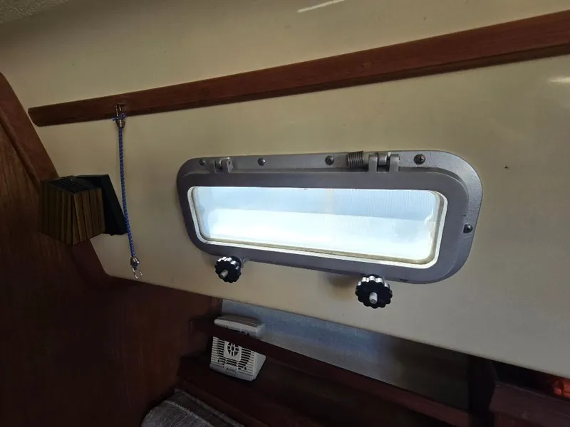 Slide: The Image of Interior view of 1986 Island Packet IP27 sailboat porthole with wooden trim. - 12