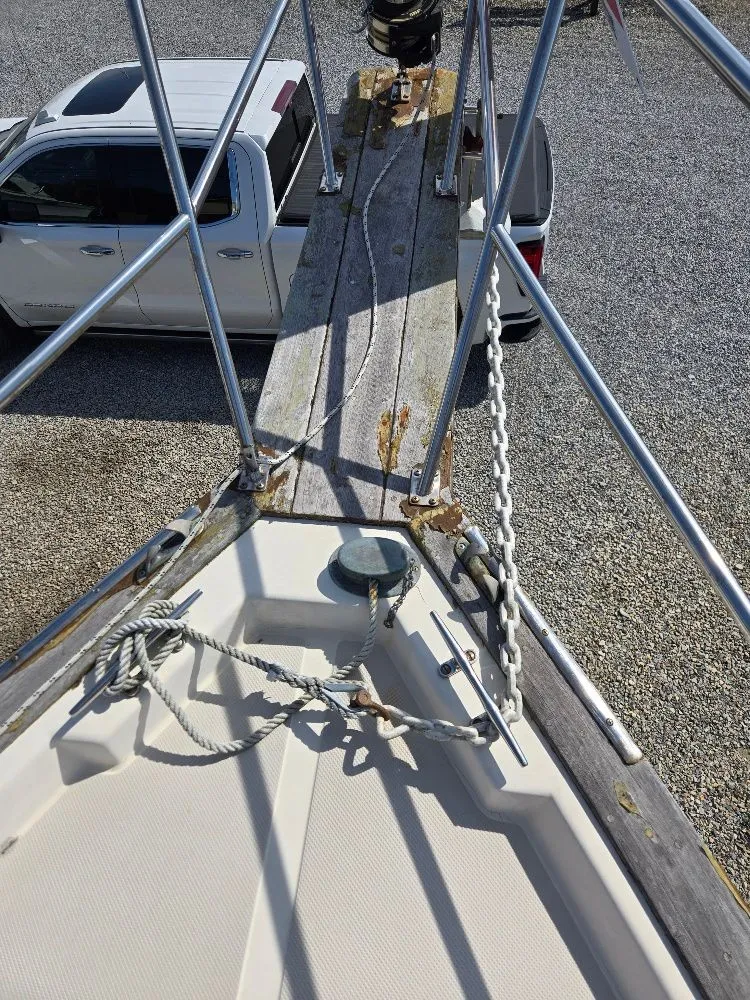 Slide: The Image of 1986 Island Packet IP27 sailboat bow with anchor chain and ropes, parked near a white truck. - 14