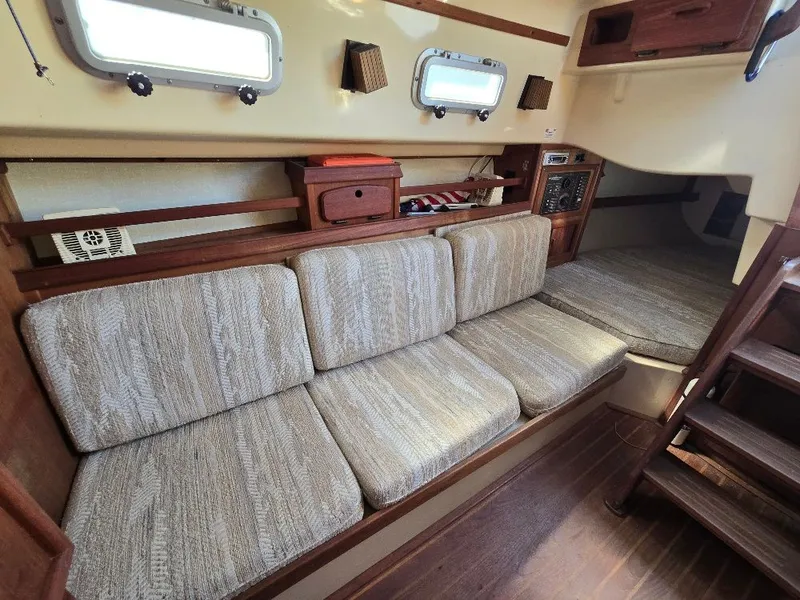 Slide: The Image of Interior of 1986 Island Packet IP27 sailboat with cushioned seating and wooden accents. - 3