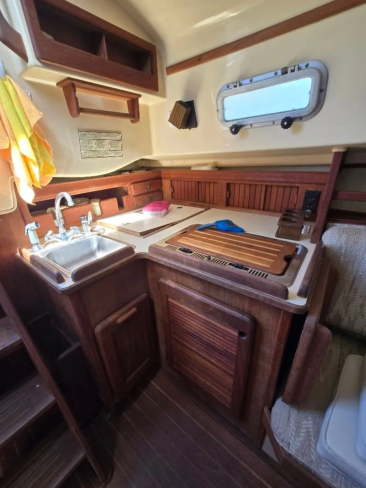 Slide: The Image of 1986 Island Packet IP27 yacht kitchen with wooden cabinetry and stainless steel sink. - 5