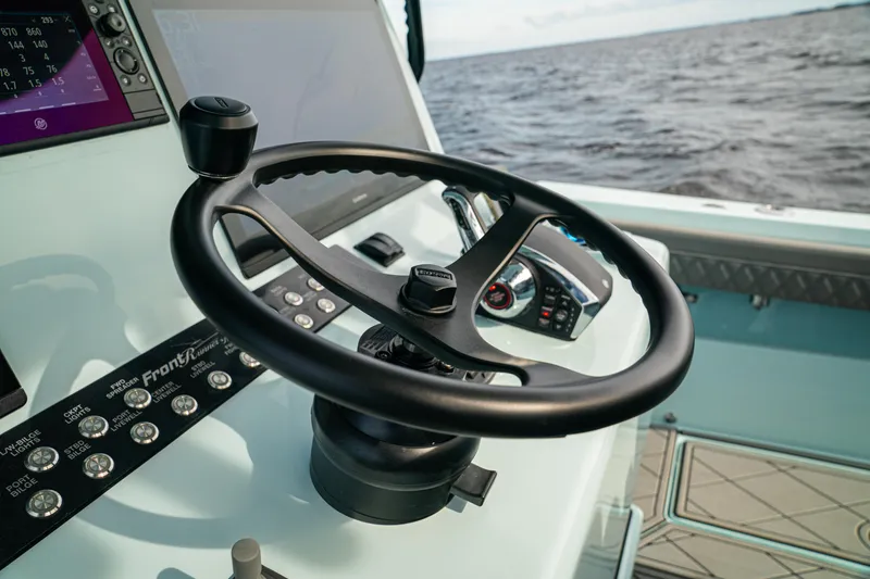 Slide: The Image of 2026 Front Runner 39 CC boat helm with steering wheel and controls, ocean in background. - 21