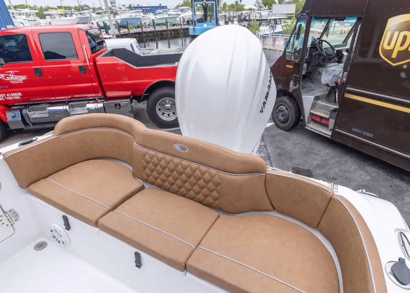 Slide: The Image of 2026 Sea Hunt Ultra 245 SE boat with tan seating, parked near red and brown trucks. - 12