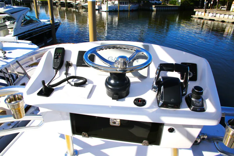 Slide: The Image of Century NAV4100 CC-H (Twins) 2025 boat helm with steering wheel and controls, docked by the water. - 43