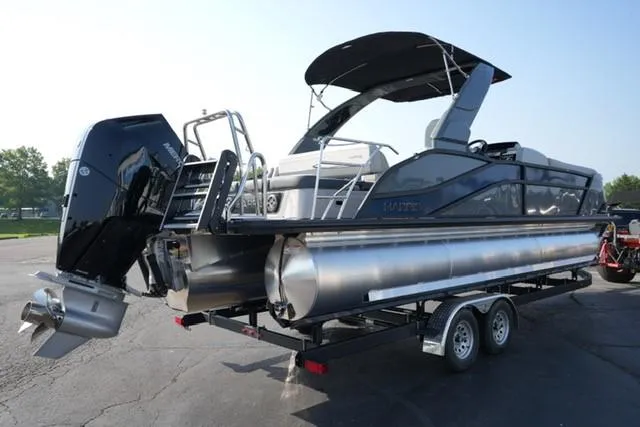 Slide: The Image of 2025 Harris Grand Mariner 250 pontoon boat on trailer, featuring sleek design and powerful outboard motor. - 21