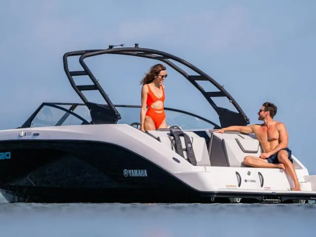 Slide: The Image of 2025 Yamaha AR220 boat with two people enjoying a sunny day on the water. - 25
