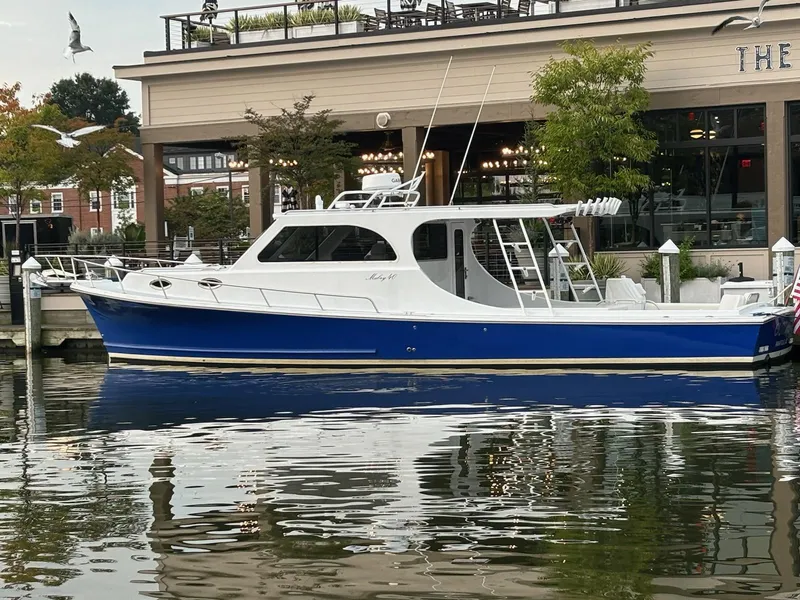 Slide: The Image of 2004 Mabry 40 boat docked by a waterfront restaurant, reflecting on calm water. - 0