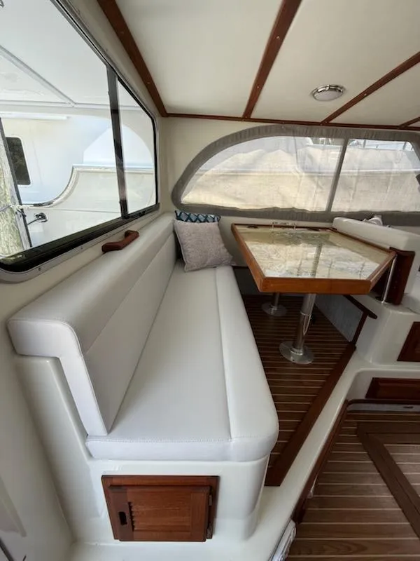 Slide: The Image of Interior of a 2004 Mabry 40 boat with cushioned seating and a wooden table. - 25