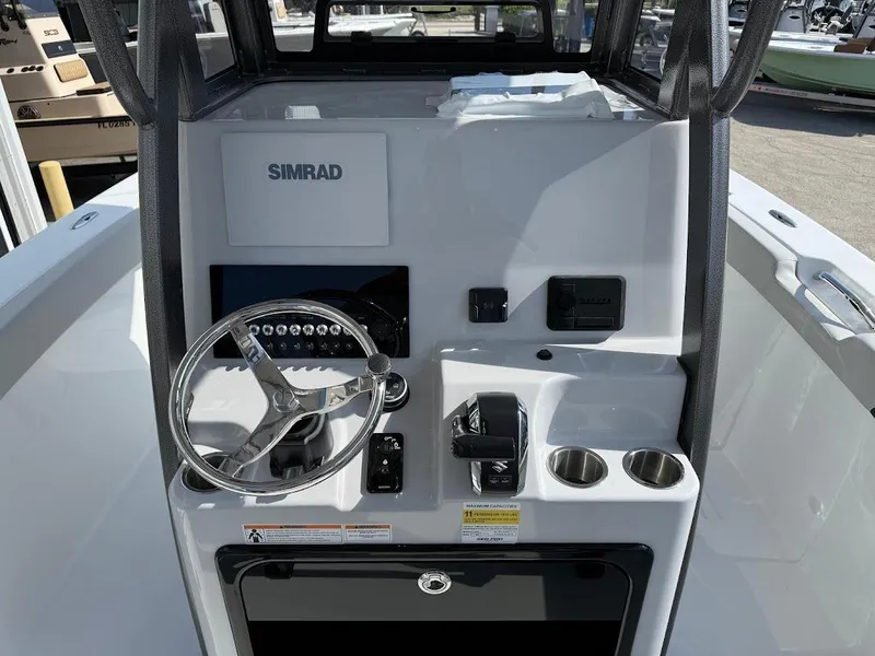 Slide: The Image of 2025 Sea Pro 242 Center Console boat dashboard with steering wheel and Simrad display. - 16
