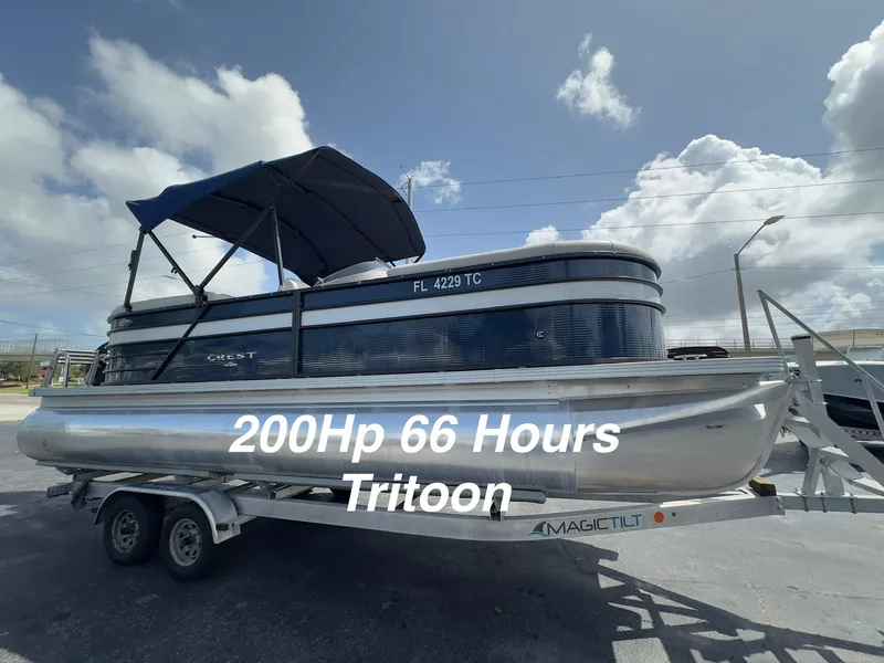 The Image of 2022 Crest Classic DLX 220 Tritoon on trailer, 200HP, 66 hours, under blue sky. - 0