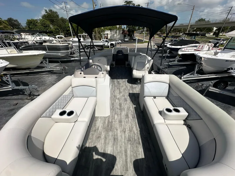 Slide: The Image of 2022 Crest Classic DLX 220 pontoon boat with spacious seating and canopy, displayed at a marina. - 11