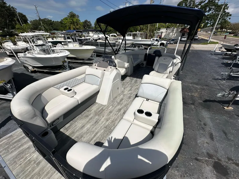 Slide: The Image of 2022 Crest Classic DLX 220 pontoon boat with spacious seating and canopy, docked at a marina. - 12