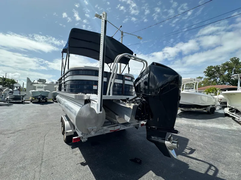 Slide: The Image of 2022 Crest Classic DLX 220 pontoon boat with Mercury outboard motor, parked outdoors. - 5