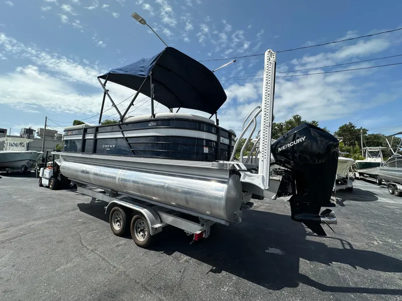 Slide: The Image of 2022 Crest Classic DLX 220 pontoon boat on trailer, featuring a Mercury outboard motor. - 6