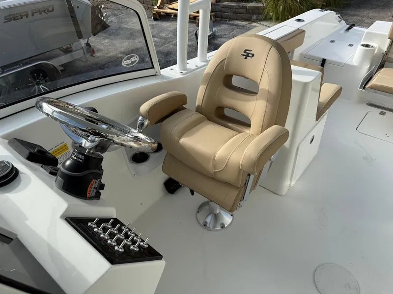 Slide: The Image of 2025 Sea Pro 240 Dual Console boat interior with beige captain's chair and steering wheel. - 8