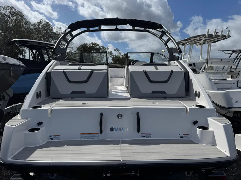 Slide: The Image of 2025 Yamaha Boats AR220, rear view, sleek design, docked under cloudy sky. - 2