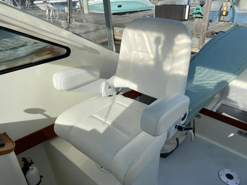 Slide: The Image of White captain's chair on 2008 Landing School Arundel 27 boat, docked with visible marina background. - 13