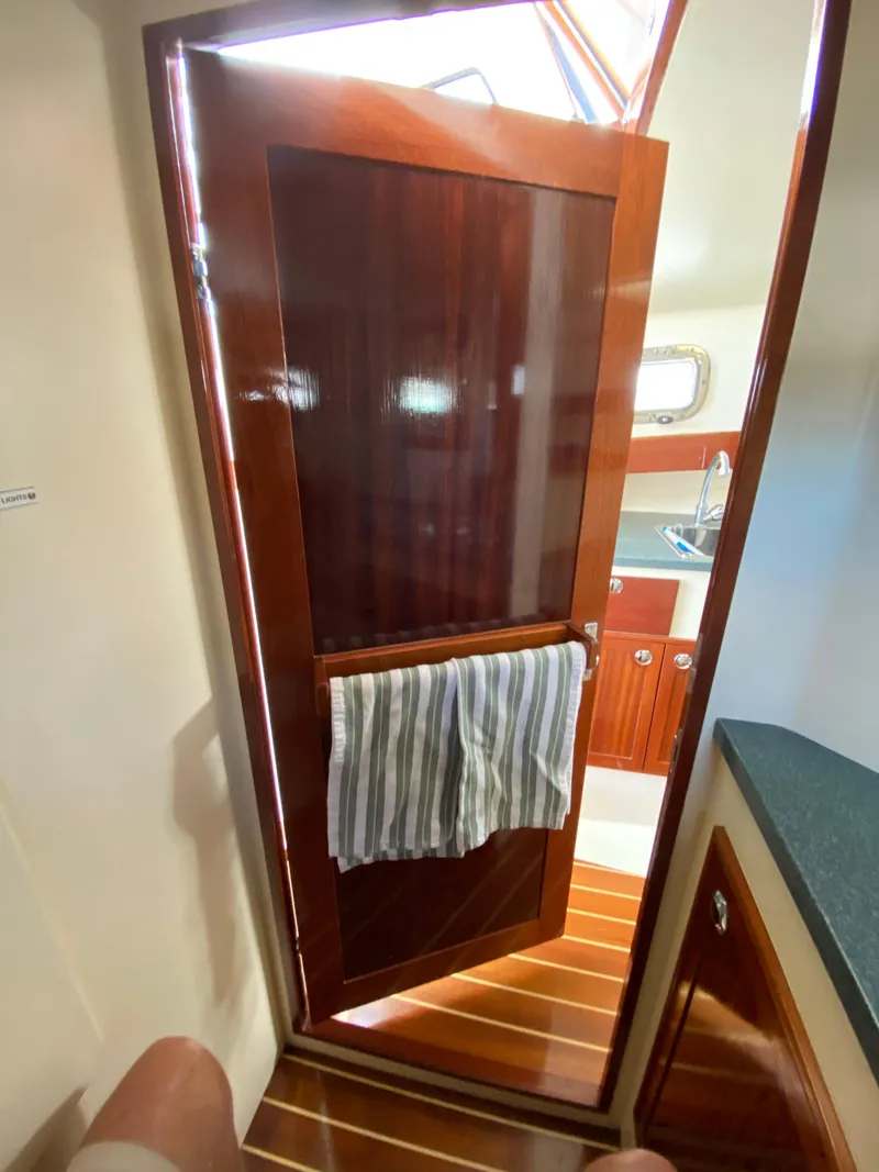 Slide: The Image of Wooden interior of 2008 Landing School Arundel 27 boat, featuring a door and striped towel. - 14