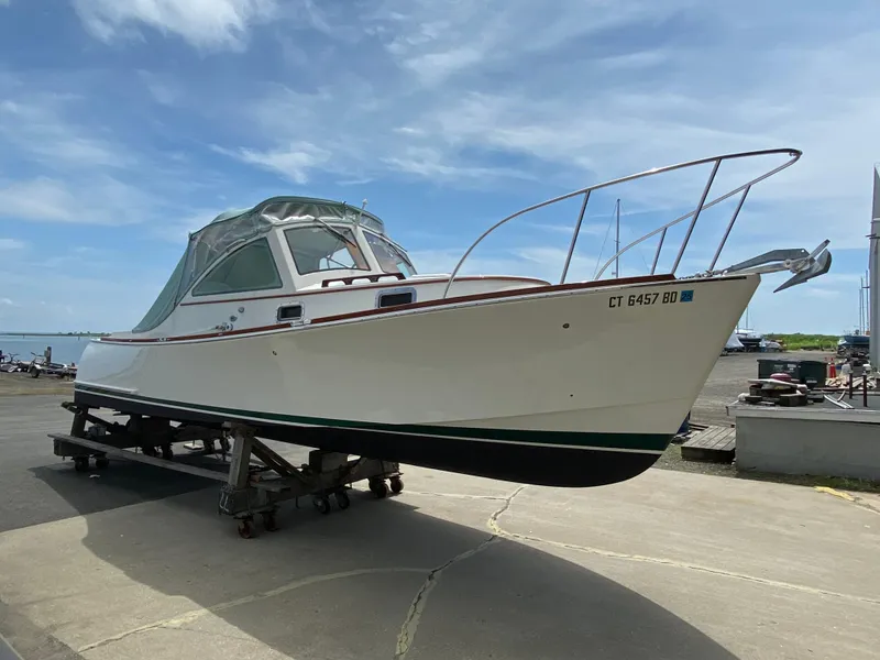 Slide: The Image of 2008 Landing School Arundel 27 boat on trailer, dockside under clear sky. - 22