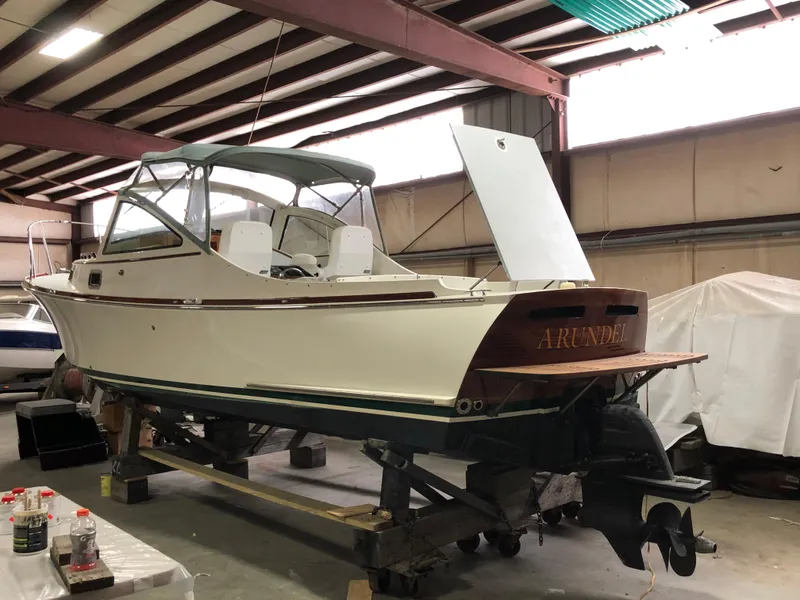 Slide: The Image of 2008 Landing School Arundel 27 boat in a workshop, partially covered, with open engine hatch. - 23