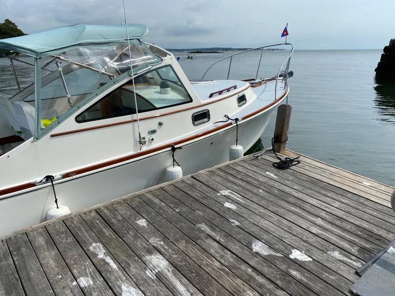 Slide: The Image of 2008 Landing School Arundel 27 boat docked by wooden pier on calm water. - 5