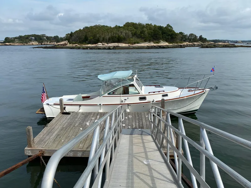 Slide: The Image of 2008 Landing School Arundel 27 boat docked by a wooden pier, calm waters, and distant island. - 9