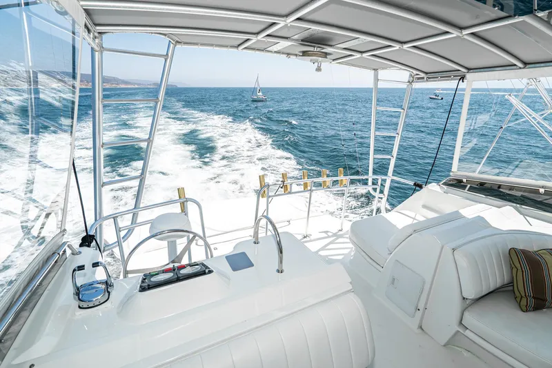 Slide: The Image of 1990 Hatteras 58 Sportfish yacht interior with ocean view, featuring white seating and helm controls. - 10