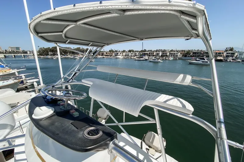 Slide: The Image of 1990 Hatteras 58 Sportfish yacht helm with canopy, overlooking marina. - 13
