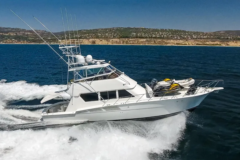 Slide: The Image of 1990 Hatteras 58 Sportfish yacht cruising on open water with jet skis on deck. - 3